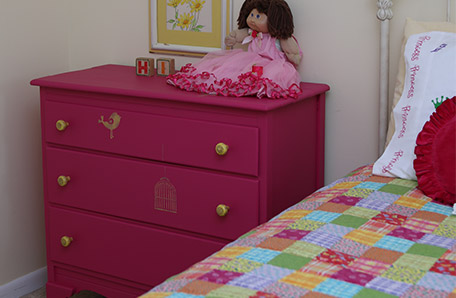 A doll in a frilly dress welcomes guests from her perch on the newly painted dresser