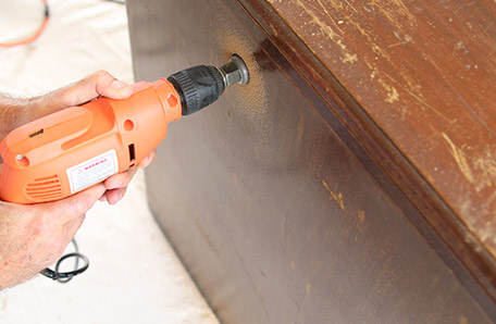 hole being drilled in top of desk for cords