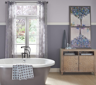 Gray bathroom with stand alone gray bathtub and floral decor.
