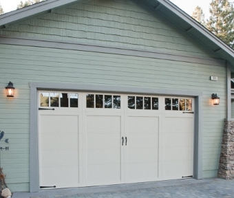 Image of exterior of a garage and garage door with teal siding.