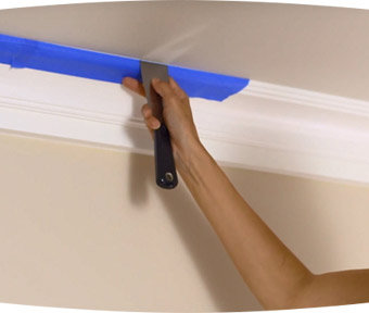 Person applying painters tape to ceiling trim