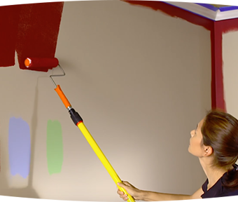 Person painting red paint with paint roller on a wall