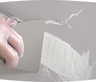 Person repairing cracked painted drywall