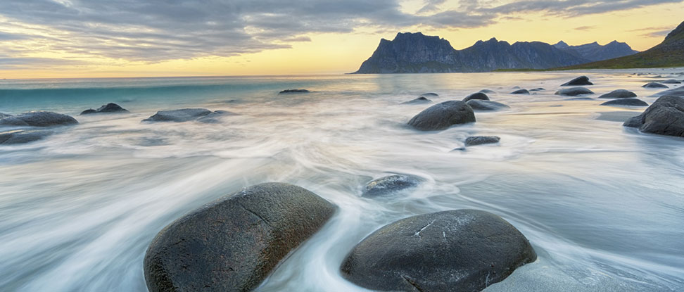 A scenic view of a beach shore with rocks and water mobile.