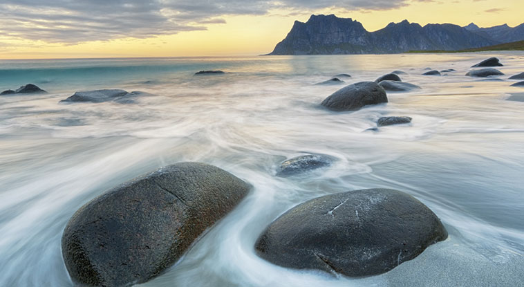 A scenic view of a beach shore with rocks and water.