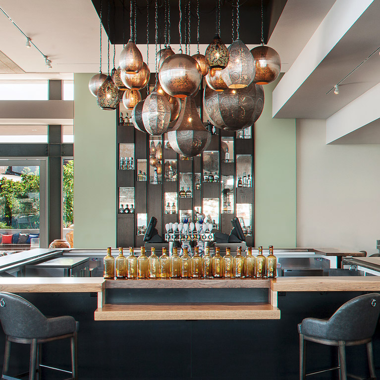 Small image of an empty modern bar. In the middle of a bar there are Moroccan lamps hanging from the ceiling and you can see the outside from the inside of the bar