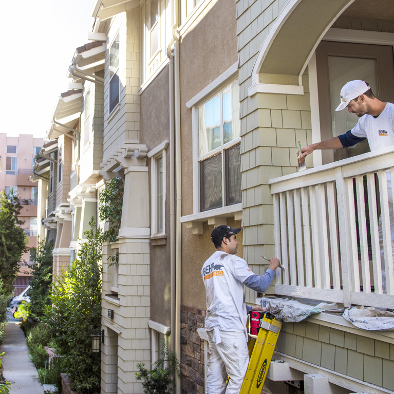 Small image a property manager and a BEHR PRO Rep looking at what the property manager is pointing at on the outside of an apartment complex. The BEHR PRO rep is taking notes on an IPAD
