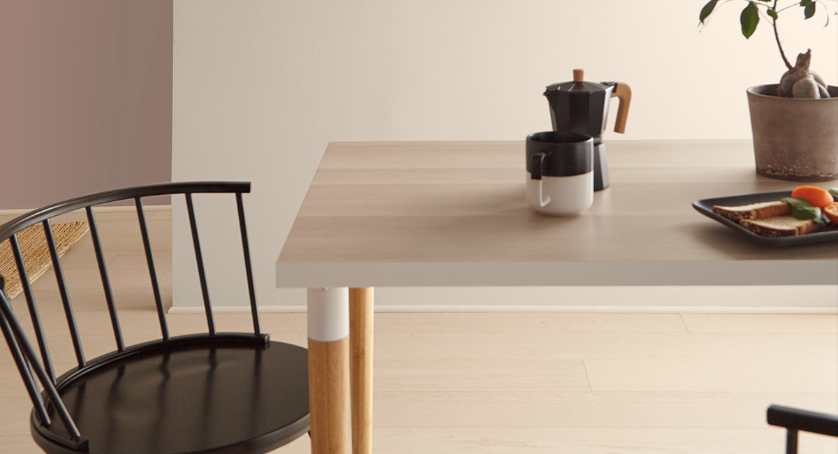 A cropped view of a table and chair. On the table is a cup of coffee, plate of food and potted plant. The scene is very casual.