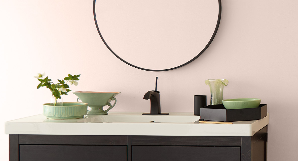 A bathroom sink with a dark cabinet, subtle green ceramic décor elements are placed atop.