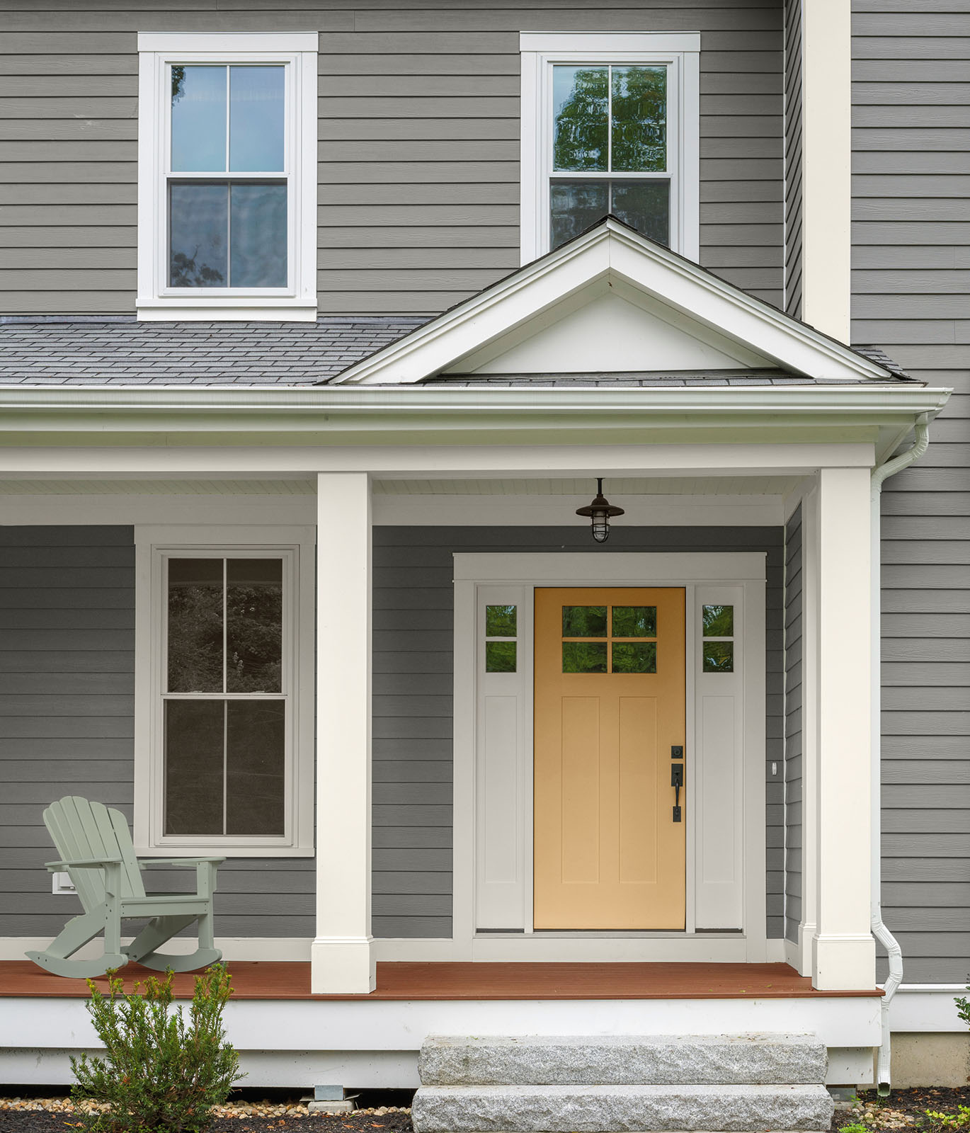 An exterior home painted in a gray color with a yellow front door.